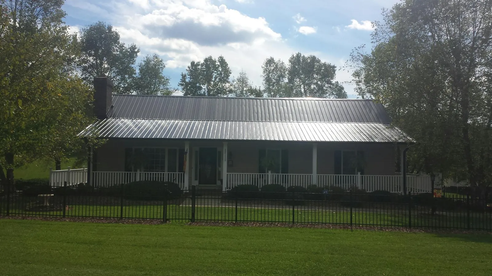 Gray metal roof on a brick ranch with a full width front porch — Gutter Guard Installation work by our crew in Gaston